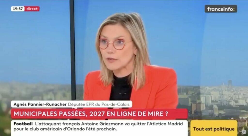 Une femme blonde avec des lunettes rondes rouges sur un plateau télé de Franceinfo TV. Elle porte une veste rouge sur un haut noir et parle avec un air sérieux. Un bandeau indique son nom : Agnès Pannier-Runacher, députée du Pas-de-Calais. Le sujet affiché à l’écran : « Municipales passées, 2027 en ligne de mire ? ».